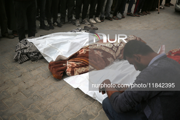 Palestinians pray by the bodies of relatives killed in Israeli strikes during a funeral at the al-Awda Hospital at the Nuseirat refugee Camp...