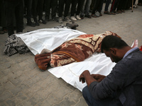 Palestinians pray by the bodies of relatives killed in Israeli strikes during a funeral at the al-Awda Hospital at the Nuseirat refugee Camp...