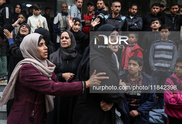 Palestinian women mourn relatives killed in an Israeli strike during their funeral at the al-Awda Hospital at the Nuseirat refugee Camp in t...