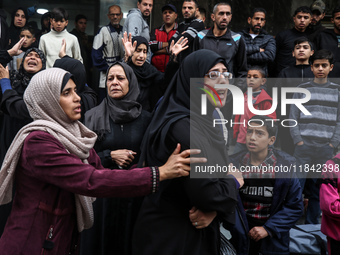 Palestinian women mourn relatives killed in an Israeli strike during their funeral at the al-Awda Hospital at the Nuseirat refugee Camp in t...