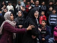 Palestinian women mourn relatives killed in an Israeli strike during their funeral at the al-Awda Hospital at the Nuseirat refugee Camp in t...