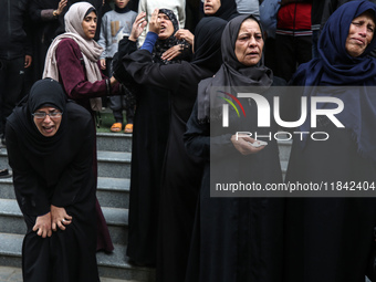 Palestinian women mourn relatives killed in an Israeli strike during their funeral at the al-Awda Hospital at the Nuseirat refugee Camp in t...