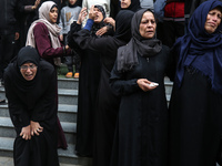 Palestinian women mourn relatives killed in an Israeli strike during their funeral at the al-Awda Hospital at the Nuseirat refugee Camp in t...