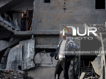 A Palestinian man stands atop the rubble of a building, destroyed in an Israeli strike, in the Nuseirat refugee Camp in the central Gaza Str...