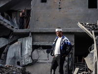 A Palestinian man stands atop the rubble of a building, destroyed in an Israeli strike, in the Nuseirat refugee Camp in the central Gaza Str...