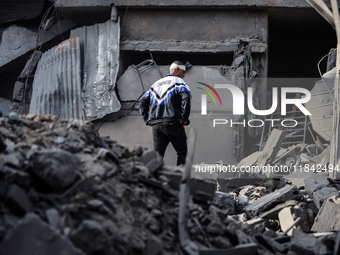 A Palestinian man stands atop the rubble of a building, destroyed in an Israeli strike, in the Nuseirat refugee Camp in the central Gaza Str...