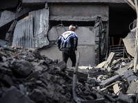 A Palestinian man stands atop the rubble of a building, destroyed in an Israeli strike, in the Nuseirat refugee Camp in the central Gaza Str...