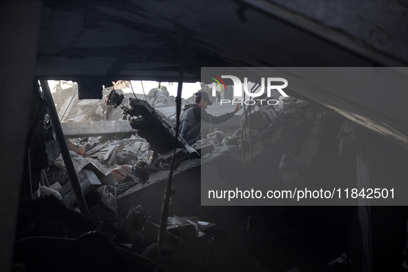 A Palestinian man stands atop the rubble of a building, destroyed in an Israeli strike, in the Nuseirat refugee Camp in the central Gaza Str...