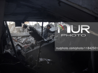 A Palestinian man stands atop the rubble of a building, destroyed in an Israeli strike, in the Nuseirat refugee Camp in the central Gaza Str...