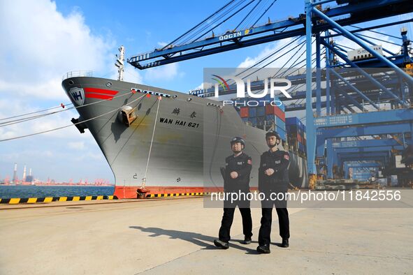 Police officers from Huangdao Border Inspection Station patrol the side of a cargo ship at the automation terminal of Qingdao Port in Qingda...