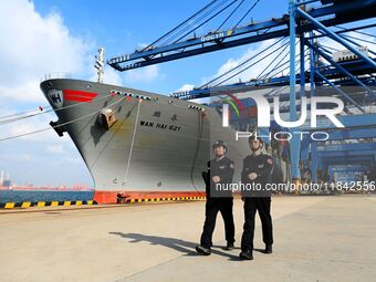 Police officers from Huangdao Border Inspection Station patrol the side of a cargo ship at the automation terminal of Qingdao Port in Qingda...