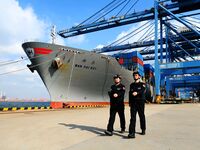 Police officers from Huangdao Border Inspection Station patrol the side of a cargo ship at the automation terminal of Qingdao Port in Qingda...