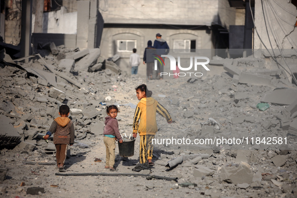 Palestinian children walk among the rubble of a building, destroyed in an Israeli strike, in the Nuseirat refugee Camp in the central Gaza S...