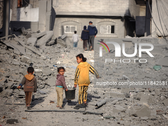 Palestinian children walk among the rubble of a building, destroyed in an Israeli strike, in the Nuseirat refugee Camp in the central Gaza S...