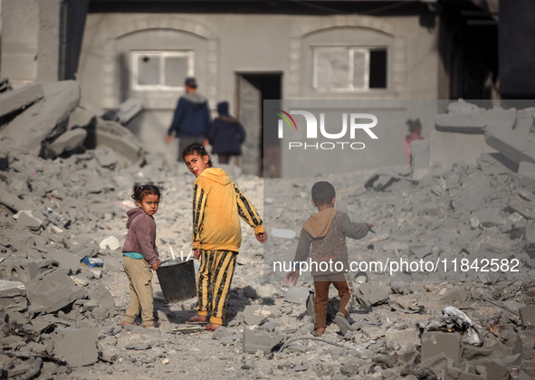 Palestinian children walk among the rubble of a building, destroyed in an Israeli strike, in the Nuseirat refugee Camp in the central Gaza S...