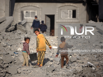 Palestinian children walk among the rubble of a building, destroyed in an Israeli strike, in the Nuseirat refugee Camp in the central Gaza S...