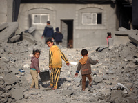 Palestinian children walk among the rubble of a building, destroyed in an Israeli strike, in the Nuseirat refugee Camp in the central Gaza S...