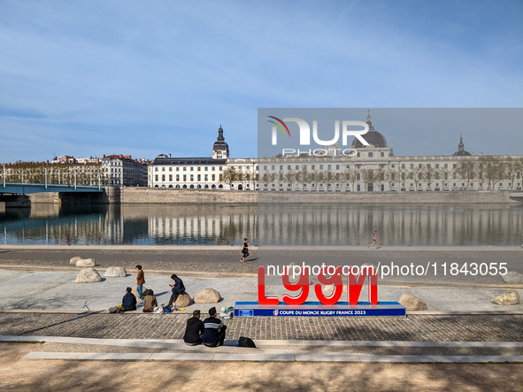 People enjoy a spring day at the riverfront in Lyon, France, on April 9, 2023, with the iconic Hôtel-Dieu building reflecting on the calm wa...