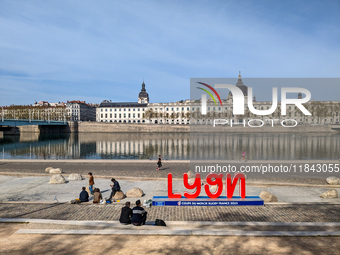 People enjoy a spring day at the riverfront in Lyon, France, on April 9, 2023, with the iconic Hôtel-Dieu building reflecting on the calm wa...