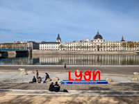 People enjoy a spring day at the riverfront in Lyon, France, on April 9, 2023, with the iconic Hôtel-Dieu building reflecting on the calm wa...