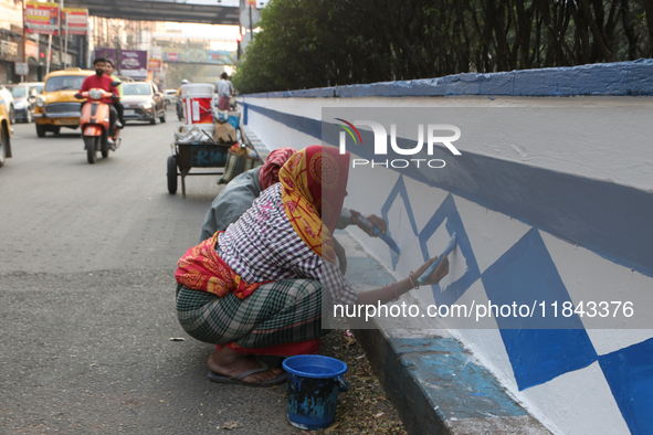 A woman migrant laborer paints a street divider in Kolkata, India, on December 7, 2024. 