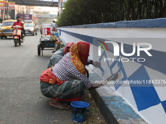 A woman migrant laborer paints a street divider in Kolkata, India, on December 7, 2024. (