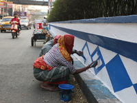 A woman migrant laborer paints a street divider in Kolkata, India, on December 7, 2024. (