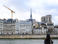 A pedestrian observes Notre-Dame Cathedral in Paris, France, from the quays. (