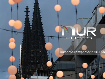 Christmas light decorations hang with the Dom Cathedral in the background in Cologne, Germany, on December 7, 2024. (