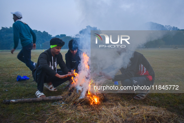 Men warm themselves by a fire on a cold winter morning in Kolkata, India, on December 8, 2024. 