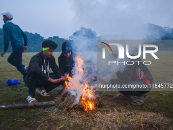 Men warm themselves by a fire on a cold winter morning in Kolkata, India, on December 8, 2024. (