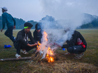 Men warm themselves by a fire on a cold winter morning in Kolkata, India, on December 8, 2024. (