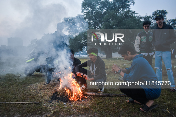 Men warm themselves by a fire on a cold winter morning in Kolkata, India, on December 8, 2024. 