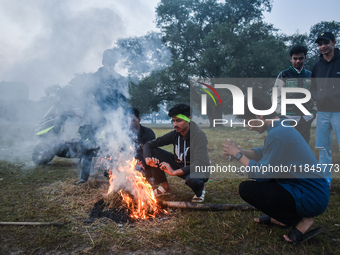 Men warm themselves by a fire on a cold winter morning in Kolkata, India, on December 8, 2024. (