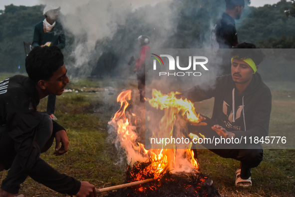 Men warm themselves by a fire on a cold winter morning in Kolkata, India, on December 8, 2024. 