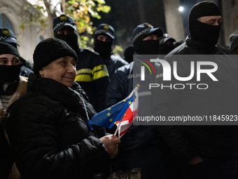 An anti-government protester carries EU and Georgian flags while facing the police during a rally for the tenth consecutive day of mass demo...