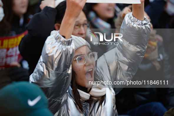 A student protests in Yeouido, Seoul, South Korea, on December 8, 2024, across from the National Assembly, holding a sign that reads, ''Pres...