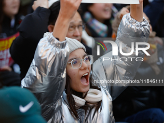 A student protests in Yeouido, Seoul, South Korea, on December 8, 2024, across from the National Assembly, holding a sign that reads, ''Pres...