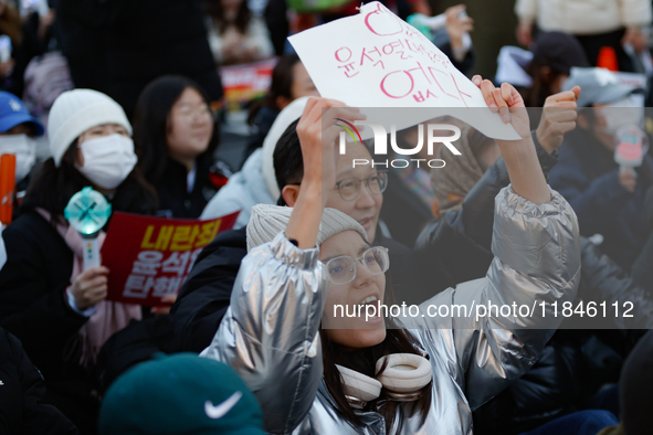 A student protests in Yeouido, Seoul, South Korea, on December 8, 2024, across from the National Assembly, holding a sign that reads, ''Pres...