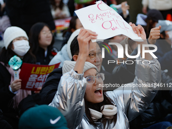 A student protests in Yeouido, Seoul, South Korea, on December 8, 2024, across from the National Assembly, holding a sign that reads, ''Pres...