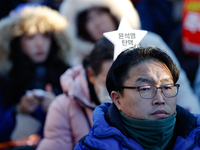 A man protests in Yeouido, Seoul, South Korea, on December 8, 2024, across from the National Assembly, holding a sign that reads, ''Impeach...