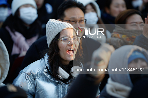 A student protests in Yeouido, Seoul, South Korea, on December 8, 2024, across from the National Assembly, holding a sign that reads, ''Pres...