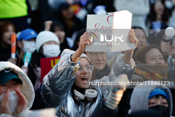 A student protests in Yeouido, Seoul, South Korea, on December 8, 2024, across from the National Assembly, holding a sign that reads, ''Pres...