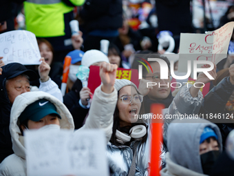 A student protests in Yeouido, Seoul, South Korea, on December 8, 2024, across from the National Assembly, holding a sign that reads, ''Pres...