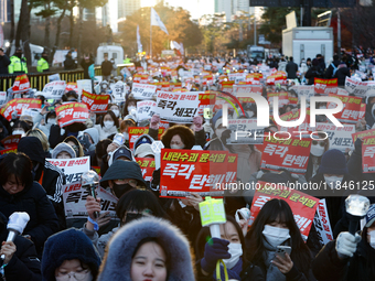 Tens of thousands of citizens gather across from the National Assembly in Yeouido, Seoul, South Korea, on December 8, 2024, holding signs th...