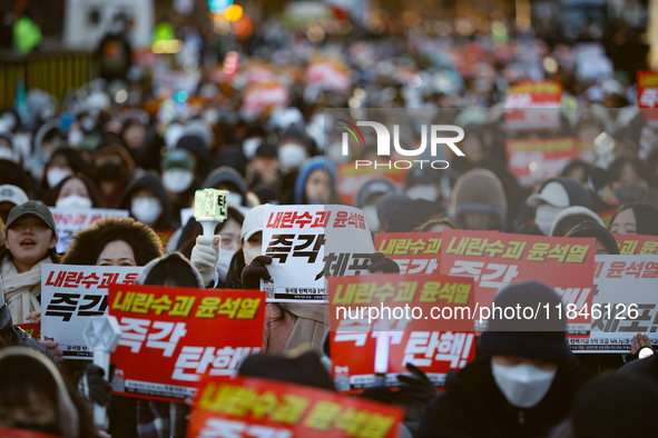 Tens of thousands of citizens gather across from the National Assembly in Yeouido, Seoul, South Korea, on December 8, 2024, holding signs th...