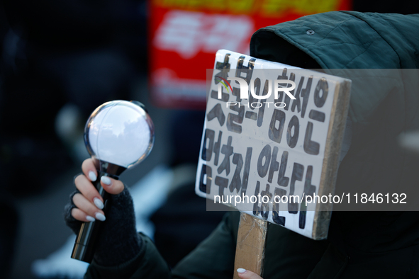 A university student protests in Yeouido, Seoul, South Korea, on December 8, 2024, across from the National Assembly, holding a sign that re...