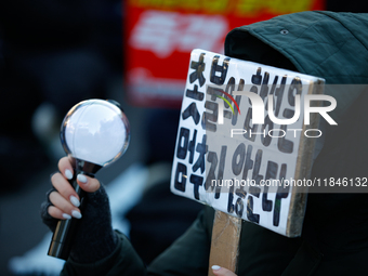 A university student protests in Yeouido, Seoul, South Korea, on December 8, 2024, across from the National Assembly, holding a sign that re...