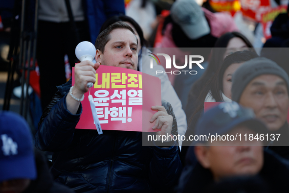 A foreign national protests in Yeouido, Seoul, South Korea, on December 8, 2024, across from the National Assembly, holding a sign that read...