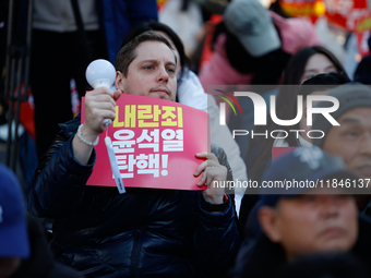 A foreign national protests in Yeouido, Seoul, South Korea, on December 8, 2024, across from the National Assembly, holding a sign that read...